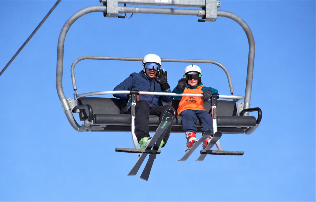 Kayak & Snowboard Kampları telesiyejde el sallayan yetişkin ve çocuk